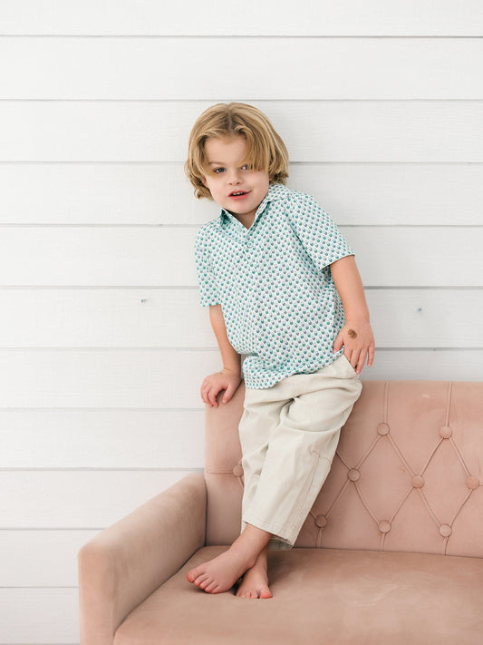 A little boy wearing a green and blue Halloween bucket print with blue buttons