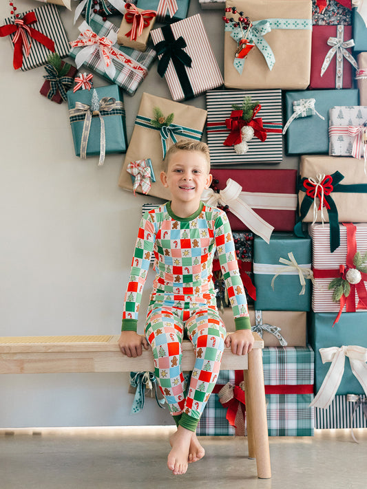 A little boy wearing the candy cane, Christmas tree, and gingerbread men bamboo pajamas