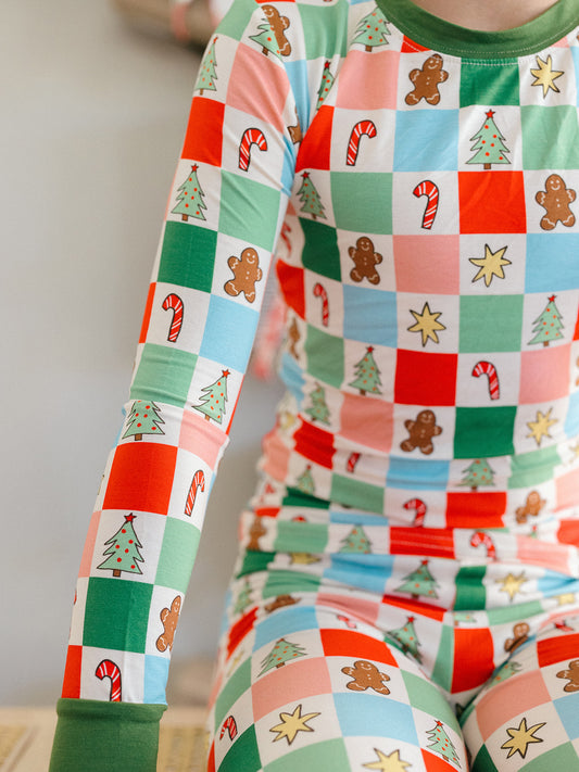 A little boy wearing the candy cane, Christmas tree, and gingerbread men bamboo pajamas