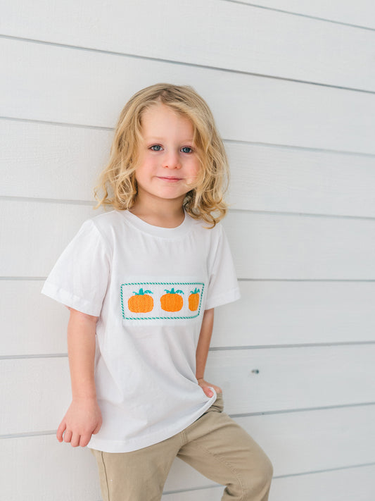 a little boy wearing a smocked pumpkin t-shirt