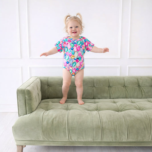 Little girl in gem t shirt bubble on a couch jumping.