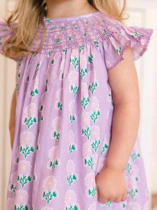 Child wearing a purple floral dress with a plain background