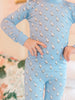 Child wearing a blue pj set with duck pattern on a blurred floral background