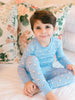 Child wearing blue pajamas with a duck pattern, sitting on a floral-patterned couch.