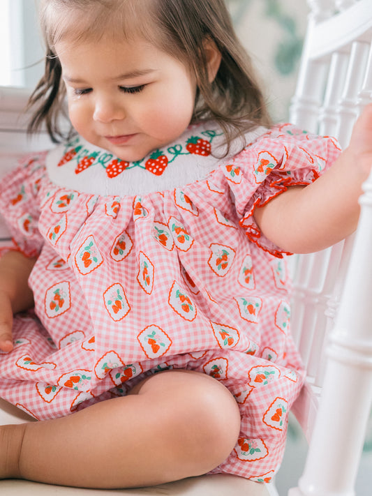 Child wearing a pink strawberry bubble with a floral pattern.