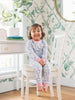 Child in pajamas sitting on a chair in a room with floral wallpaper
