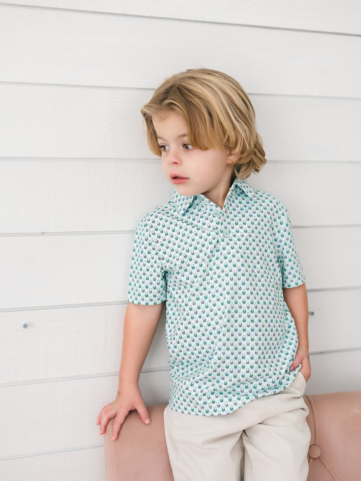 A little boy wearing a green and blue Halloween bucket print with blue buttons