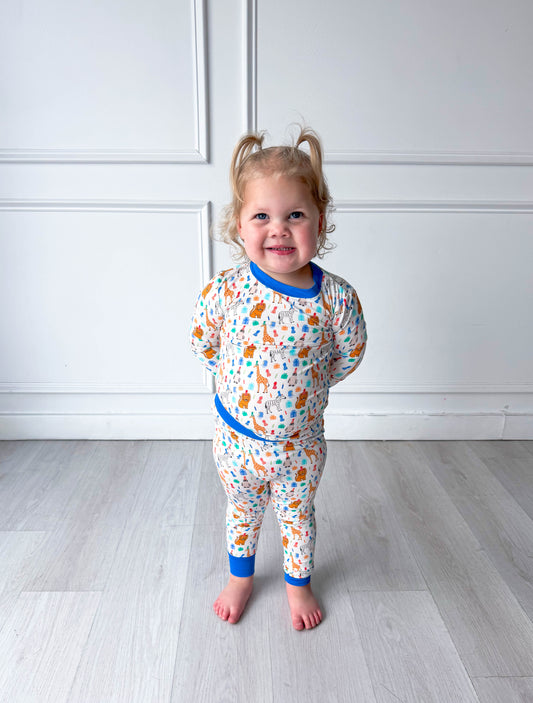 Child wearing a colorful party animal pajama set with a white wall background
