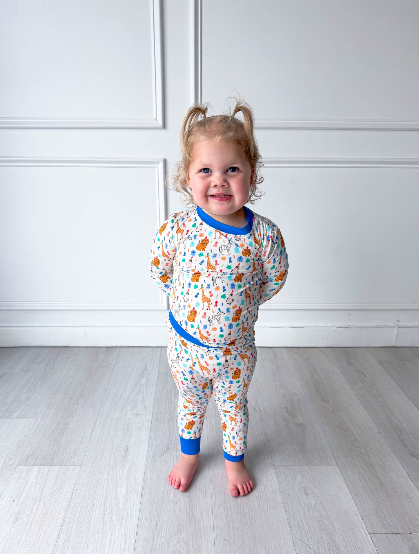 Child wearing a colorful party animal pajama set with a white wall background