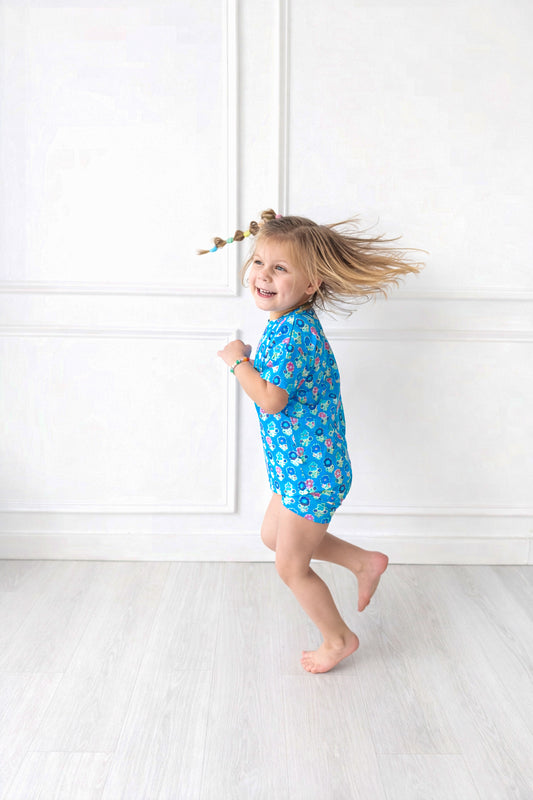 Child wearing a blue biker short set with a pattern of flowers on a white background
