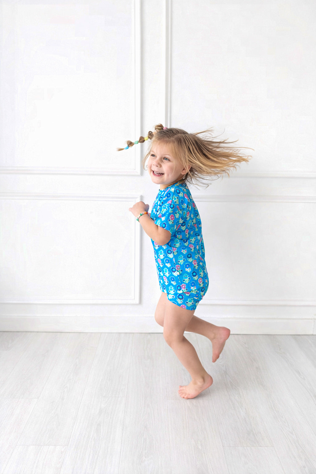 Child wearing a blue biker short set with a pattern of flowers on a white background