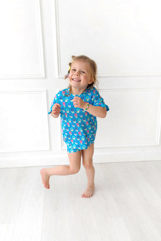 Child wearing a blue biker short set with a pattern of flowers on a white background