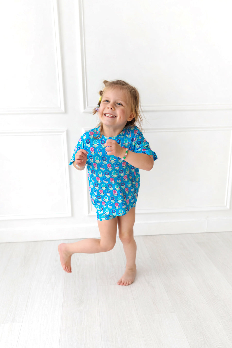 Child wearing a blue biker short set with a pattern of flowers on a white background
