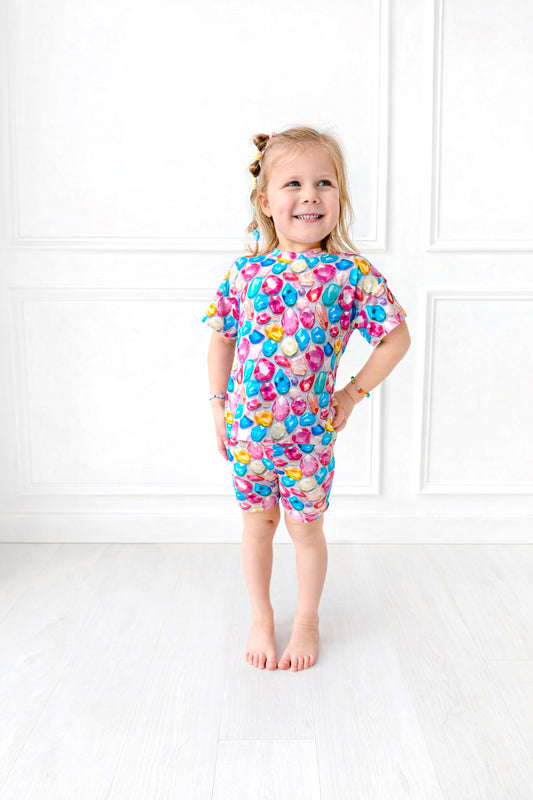 Young girl wearing a colorful gem patterned outfit against a white background