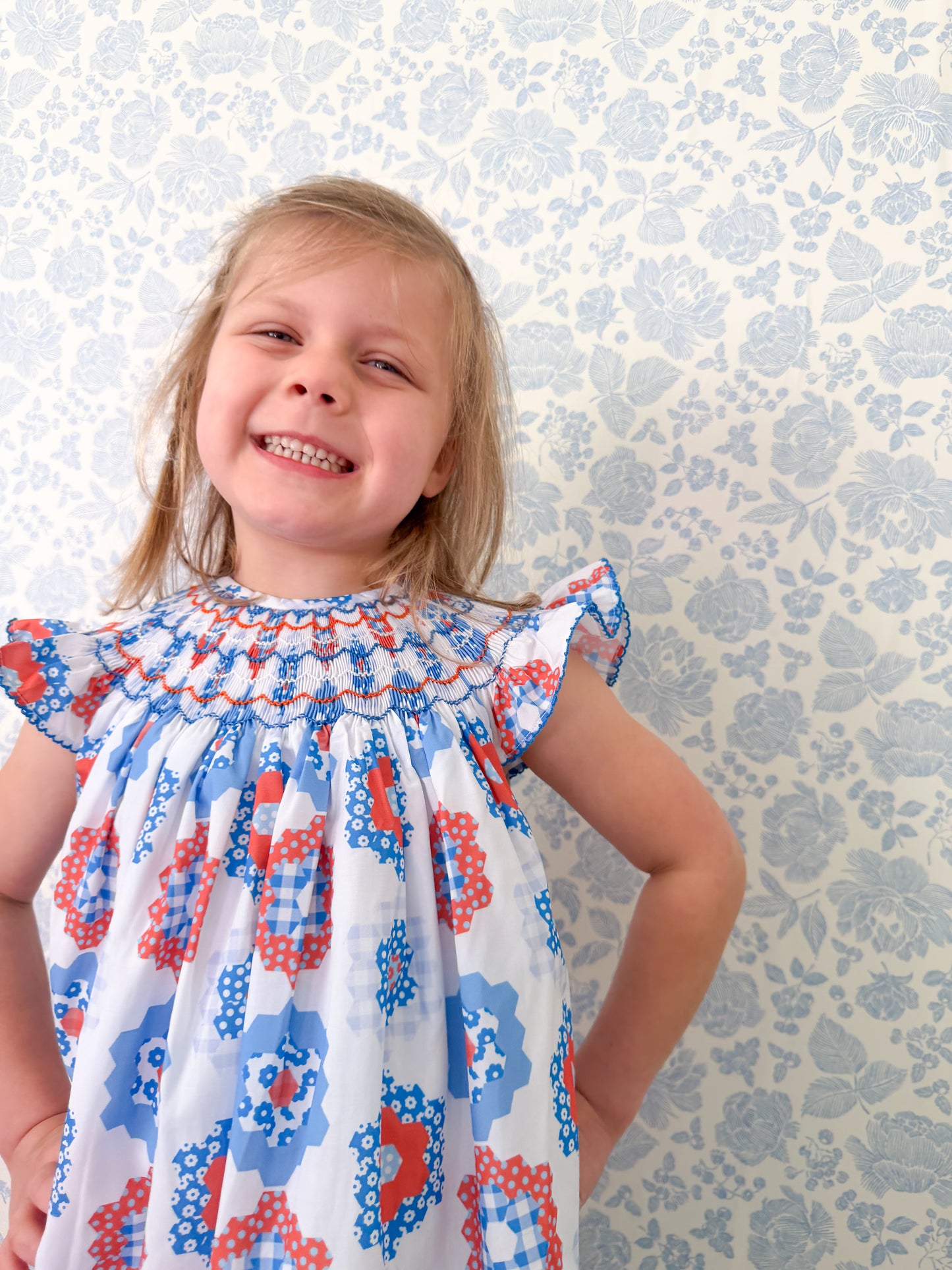 young girl wearing a red white and blue hand smocked dress