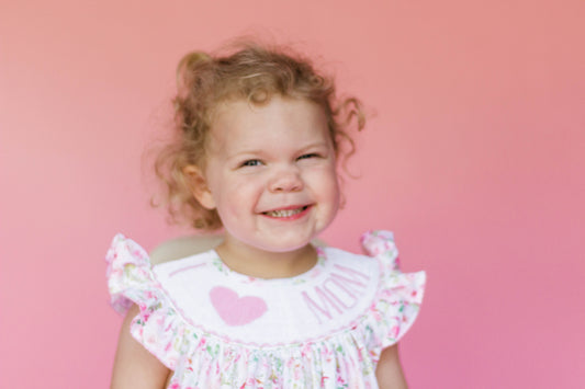Toddler modeling pink floral outfit with "I [heart] MOM" on smock plate